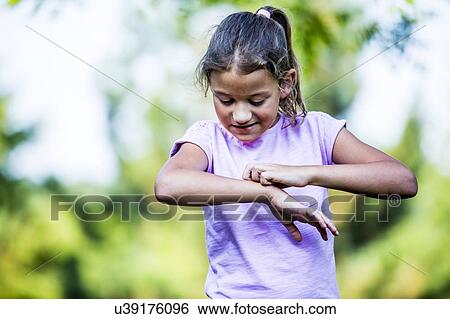Stock Photograph - Girl scratching her hand in park.. Fotosearch