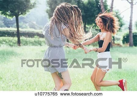 Stock Photography - Girlfriends dancing in park. Fotosearch