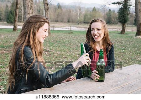 Girlfriends drinking beer in park View Large Photo Image Stock Photograph - Girlfriends drinking beer in park. Fotosearch