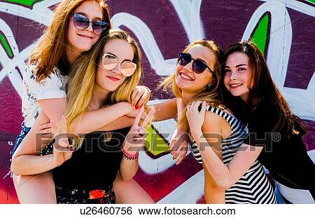 Stock Photograph - Girlfriends frolicking against graffiti wall. Fotosearch