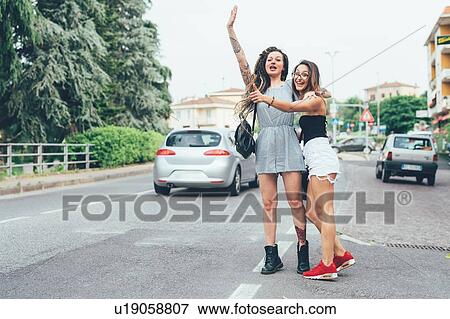 Stock Photo - Girlfriends hailing cab in middle of road. Fotosearch