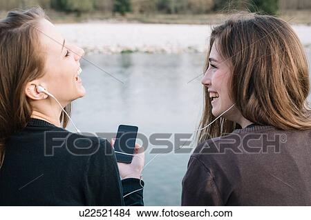 Picture - Girlfriends listening to music in park. Fotosearch