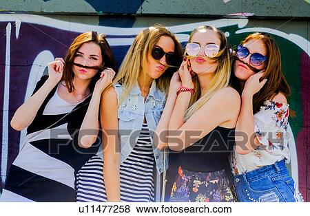 Girlfriends making faces against graffiti wall View Large Photo Image Stock Photo - Girlfriends making faces against graffiti wall. Fotosearch