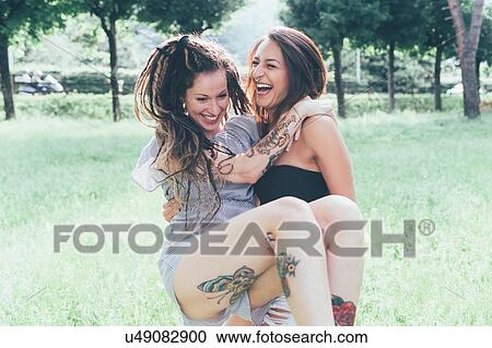 Stock Image - Girlfriends playing in park. Fotosearch