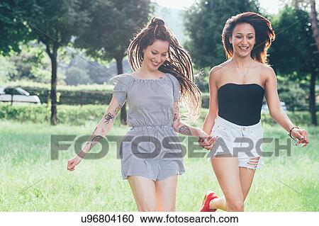 Stock Image - Girlfriends playing in park. Fotosearch