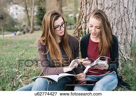 Stock Photo - Girlfriends reading book in park. Fotosearch