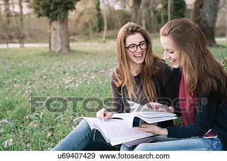 Stock Photo - Girlfriends reading book in park. Fotosearch