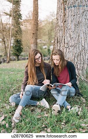 Stock Photography - Girlfriends reading book in park. Fotosearch