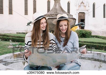 Stock Image - Girlfriends reading street map at piazza, Belluno, Veneto, Italy. Fotosearch