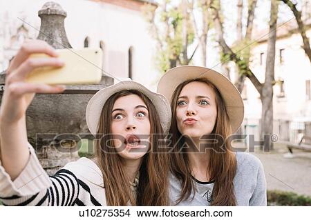 Picture - Girlfriends taking selfie at piazza, Belluno, Veneto, Italy. Fotosearch