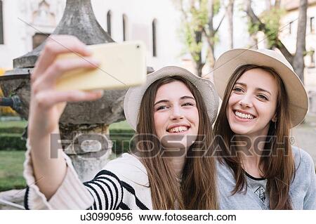 Stock Photograph - Girlfriends taking selfie at piazza, Belluno, Veneto, Italy. Fotosearch