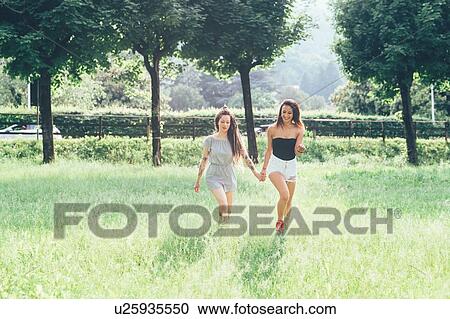 Stock Image - Girlfriends walking in park. Fotosearch