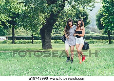 Stock Photograph - Girlfriends walking in park. Fotosearch