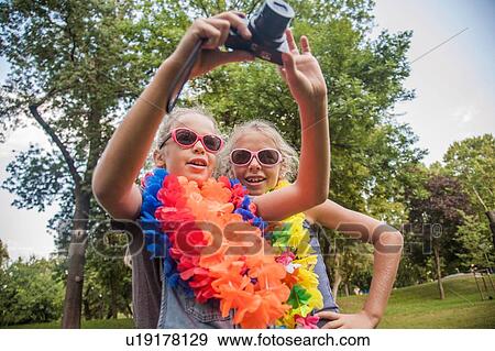 Stock Photo - Girls in costume taking photograph with camera. Fotosearch