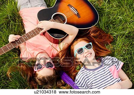 Stock Photo - Girls playing guitar on grass. Fotosearch