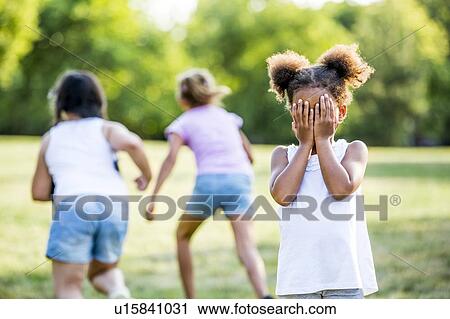 Stock Image - Girls playing hide and seek game in park.. Fotosearch
