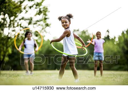 Girls playing with hula hoops in park. View Large Photo Image Stock Image - Girls playing with hula hoops in park.. Fotosearch