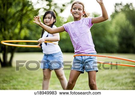 Girls playing with hula hoops in park. View Large Photo Image Stock Image - Girls playing with hula hoops in park.. Fotosearch