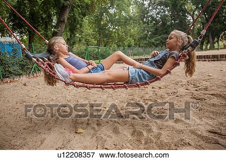 Stock Photo - Girls relaxing on net swing. Fotosearch