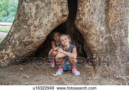 Girls squatting inside hollow in tree View Large Photo Image Stock Photo - Girls squatting inside hollow in tree. Fotosearch