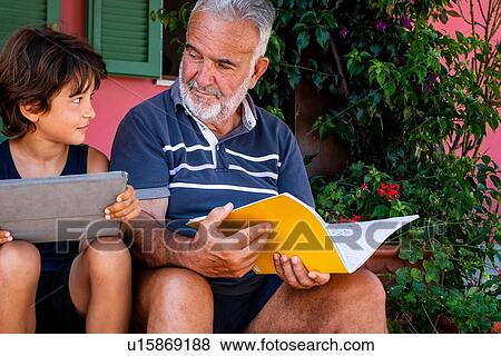 Stock Photo - Grandfather sitting with grandson on front door steps. Fotosearch