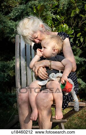 Stock Image - Grandmother and toddler in garden. Fotosearch