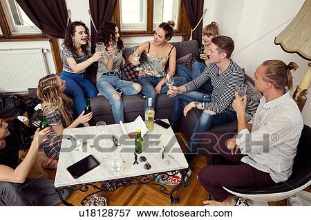Group of male and female adult friends sitting on sofa making a toast View Large Photo Image Stock Photo - Group of male and female adult friends sitting on sofa making a toast. Fotosearch