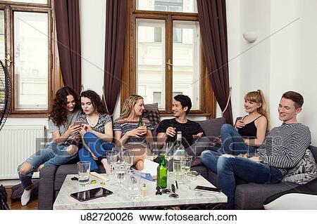 Group of male and female adult friends sitting on sofa chatting and drinking View Large Photo Image Stock Photograph - Group of male and female adult friends sitting on sofa chatting and drinking. Fotosearch