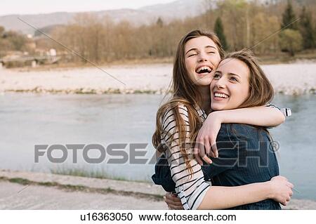 Stock Image - Happy girlfriends by river, Belluno, Veneto, Italy. Fotosearch