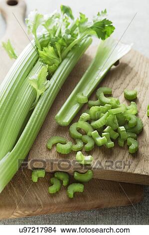 Head of celery on a wooden chopping board with slices of celery lying next to it. View Large Photo Image Picture - Head of celery on a wooden chopping board with slices of celery lying next to it.. Fotosearch