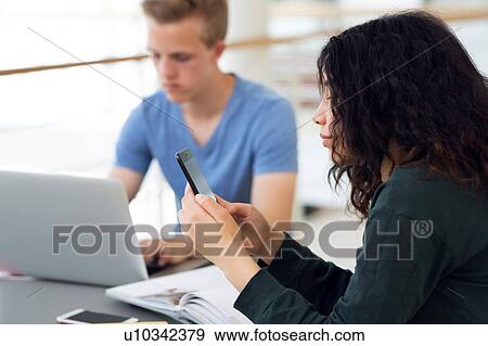 High school girl at classroom desk looking at smartphone View Large Photo Image Stock Photo - High school girl at classroom desk looking at smartphone. Fotosearch