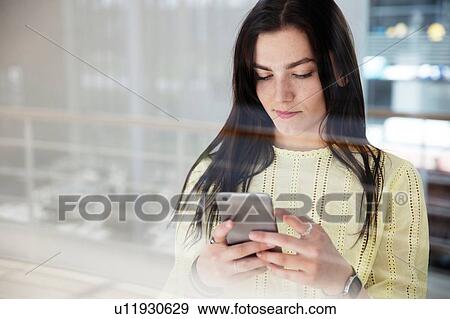 Stock Photo - High school girl in school lobby looking at smartphone. Fotosearch