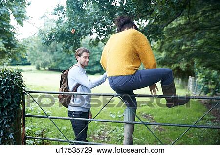 Stock Photo - Hiker couple climbing over farm gate. Fotosearch