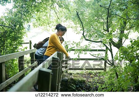 Stock Image - Hiker couple looking over wooden bridge. Fotosearch