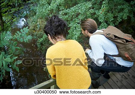 Hiker couple looking over wooden bridge View Large Photo Image Stock Image - Hiker couple looking over wooden bridge. Fotosearch