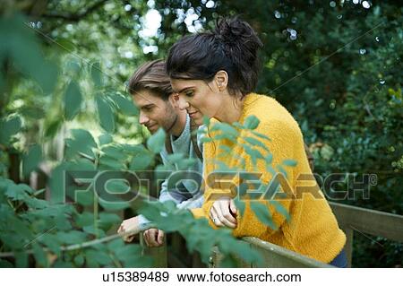 Stock Photo - Hiker couple looking over wooden bridge. Fotosearch