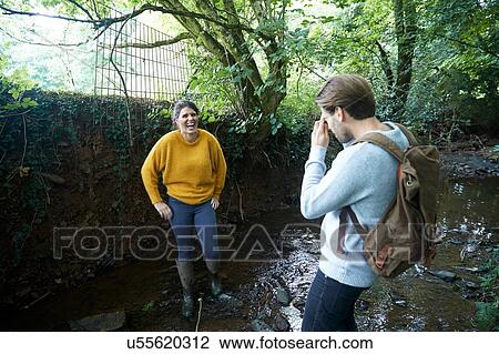 Stock Image - Hiker couple taking photograph in stream. Fotosearch