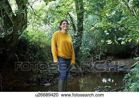 Stock Image - Hiker standing in stream. Fotosearch