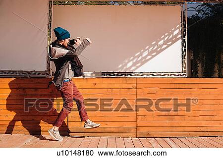 Stock Image - Hipster dancing on wooden decking by stage. Fotosearch