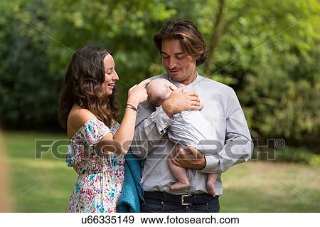 Stock Photo - Husband and wife with baby in garden. Fotosearch