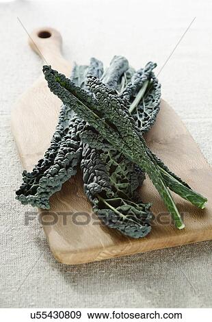 Stock Photo - Kale 'Brassica oleracea', or Cavolo nero, on a wooden chopping board.. Fotosearch
