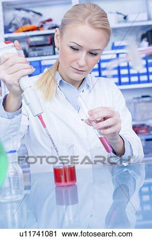 Stock Image - Laboratory assistant pipetting liquid into test tube.. Fotosearch