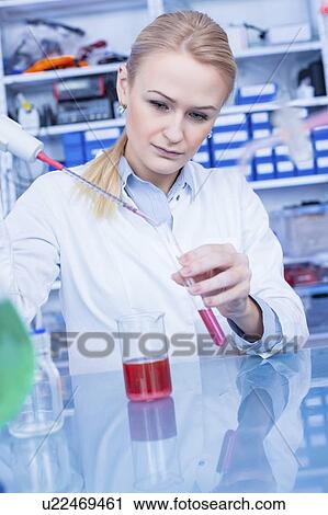 Stock Image - Laboratory assistant pipetting liquid into test tube.. Fotosearch