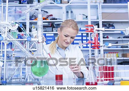 Stock Photograph - Laboratory assistant with chemical experiment.. Fotosearch
