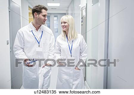 Male and female doctors in white coats walking down corridor. View Large Photo Image Stock Photography - Male and female doctors in white coats walking down corridor.. Fotosearch