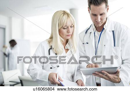 Male and female doctors inspecting digital tablet. View Large Photo Image Picture - Male and female doctors inspecting digital tablet.. Fotosearch