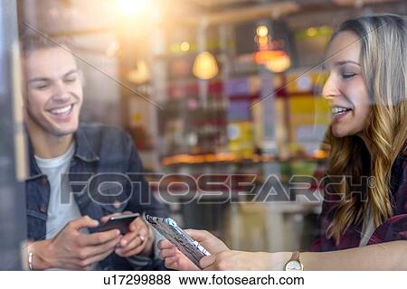 Male and female students looking at smartphones in cafe window seat, view through window View Large Photo Image Stock Photo - Male and female students looking at smartphones in cafe window seat, view through window. Fotosearch