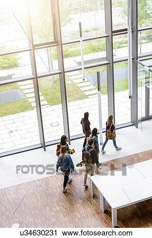 Stock Image - Male and female university students departing in university lobby, high angle view. Fotosearch