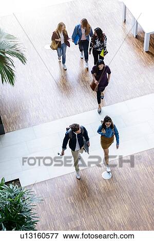 Male and female university students walking and talking in university lobby, high angle view View Large Photo Image Stock Photo - Male and female university students walking and talking in university lobby, high angle view. Fotosearch