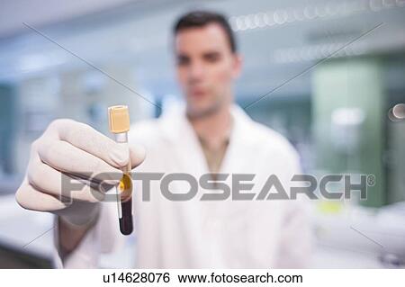 Stock Photograph - Male laboratory assistant holding test tube.. Fotosearch